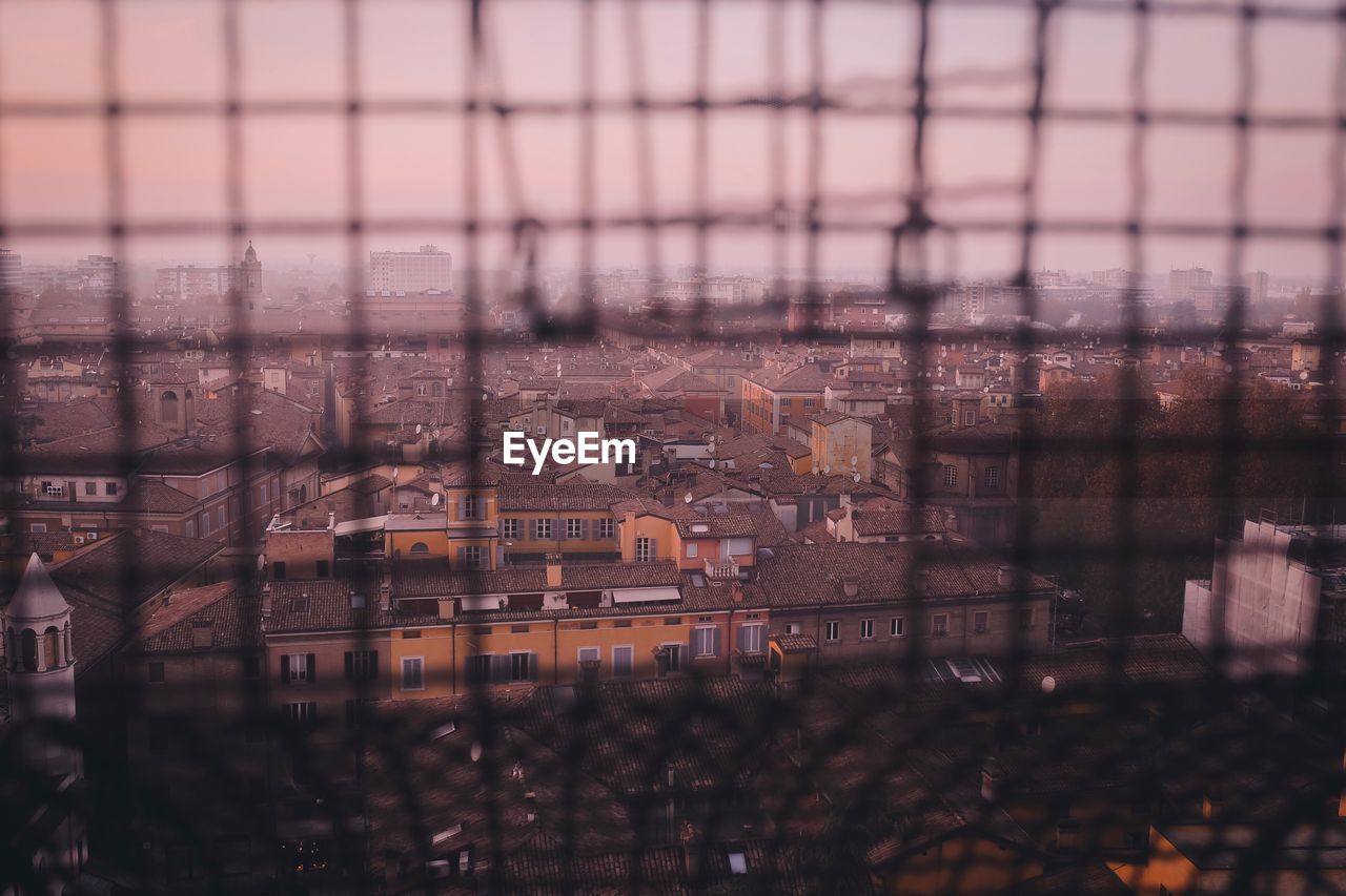 Cityscape seen through glass fence during sunset