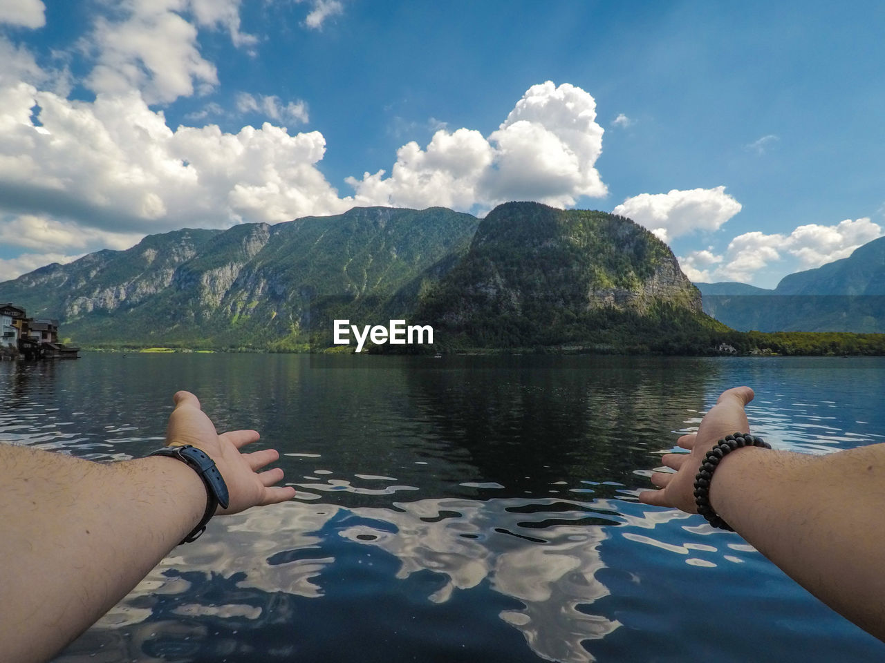 Cropped image of hand on lake against mountain range