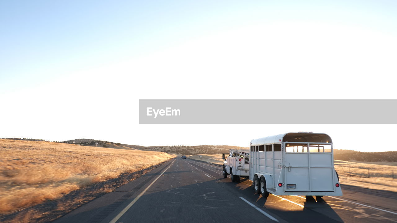 Road amidst land against clear sky