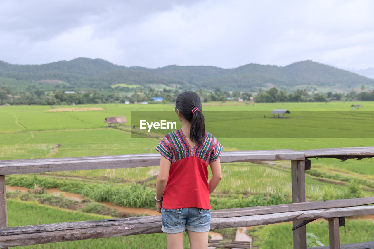 Woman looking at agricultural field against sky