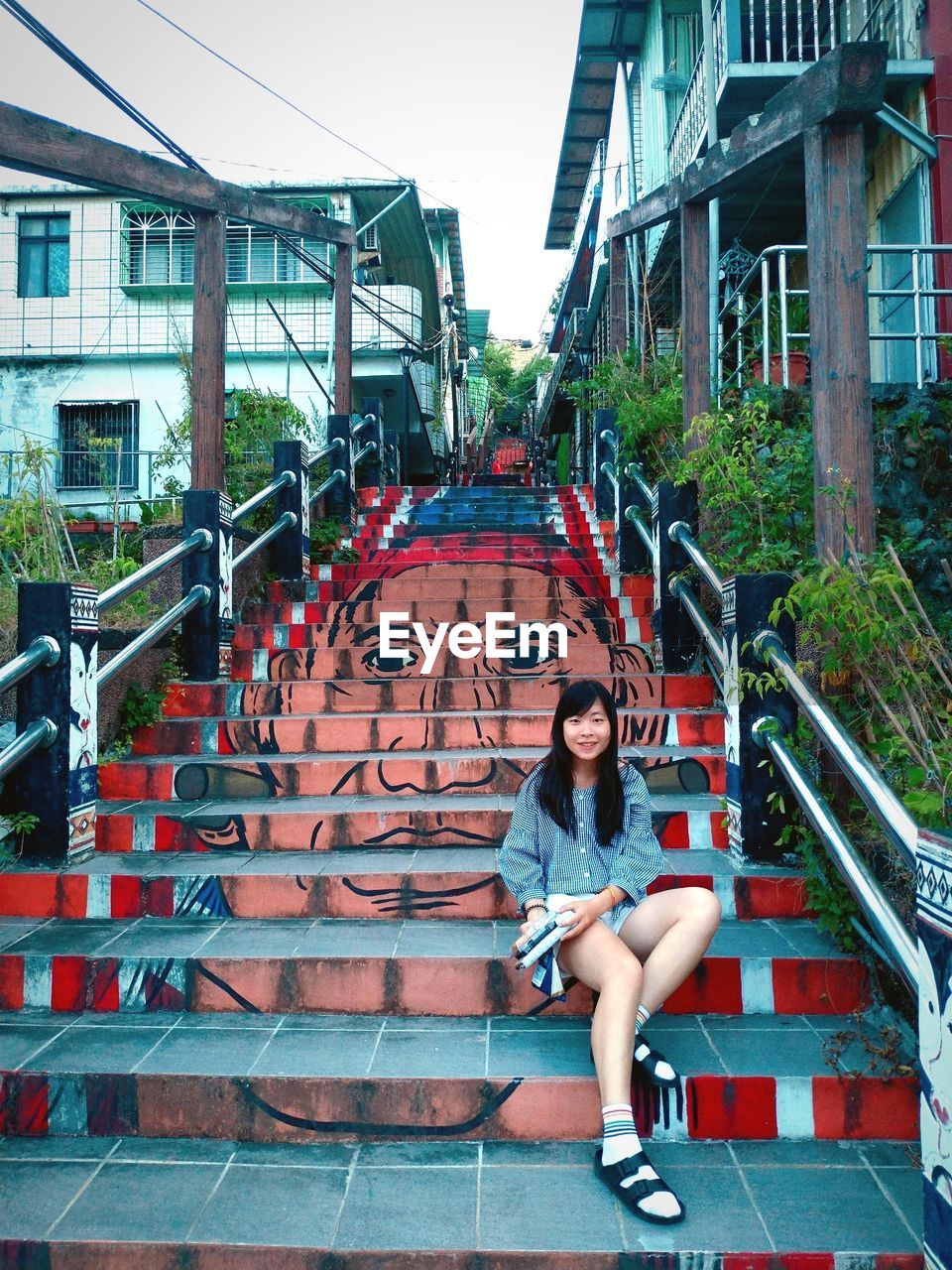 Portrait of smiling young woman sitting on steps with graffiti