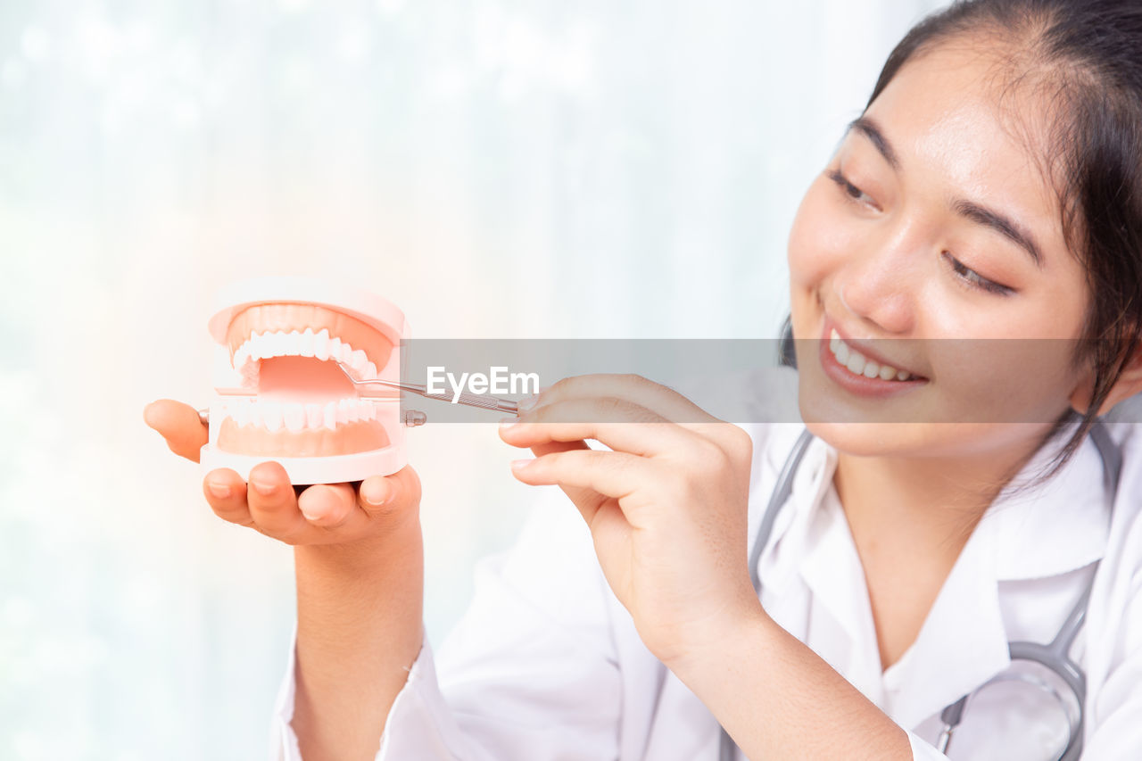 Close-up of smiling doctor holding dental implant in clinic