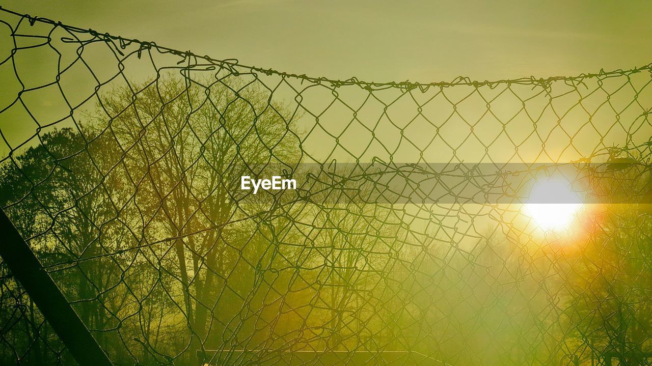 View of chainlink fence against sky during sunset