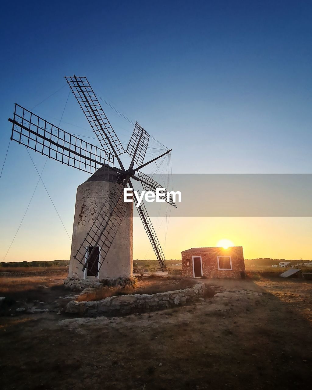 Low angle view of a windmill against sky during sunset