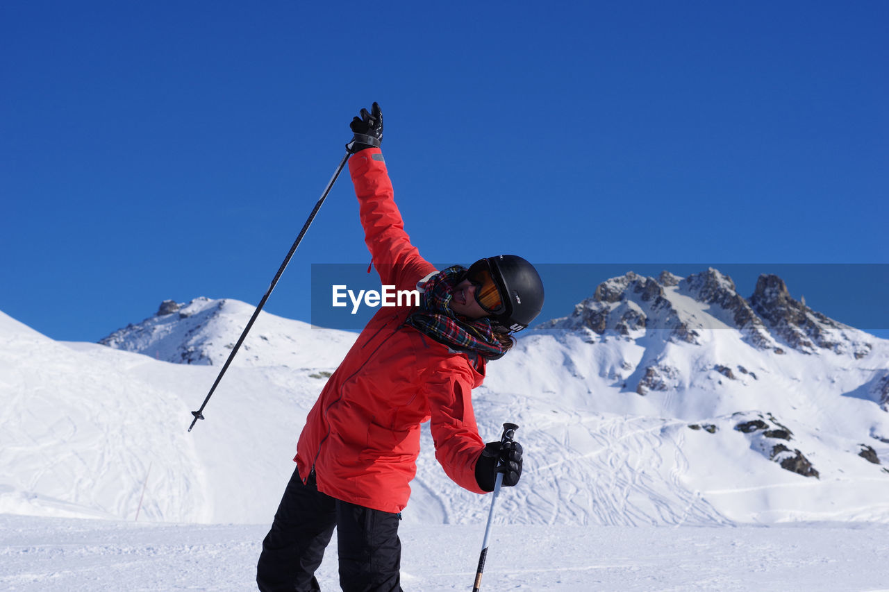 Rear view of woman on snowcapped mountain against clear sky