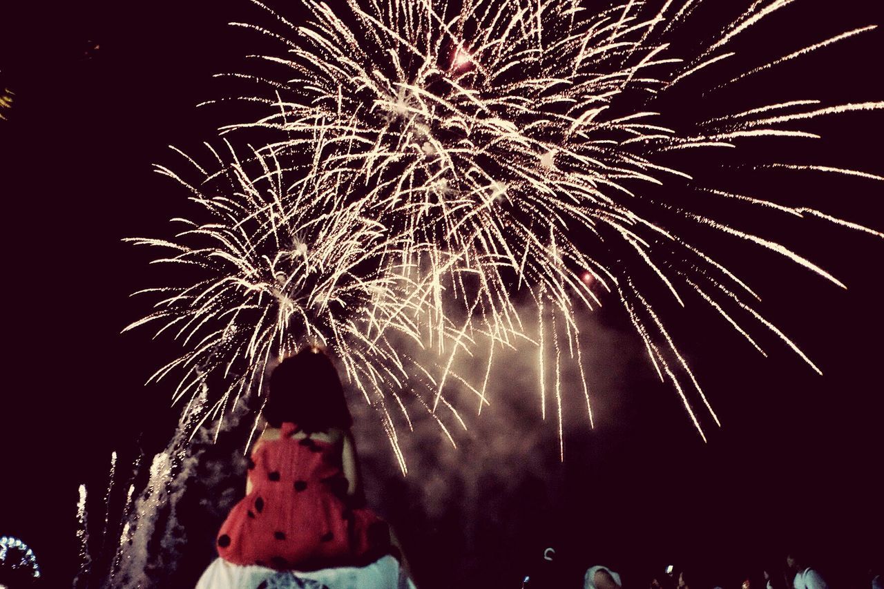 Rear view of girl sitting on shoulder looking at firework in sky
