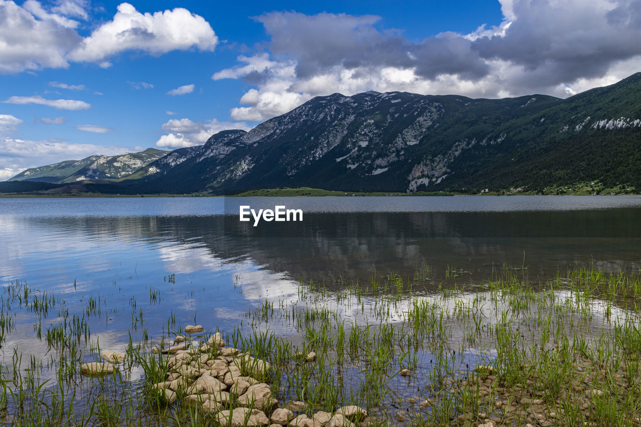 Scenic view of lake by mountains against sky