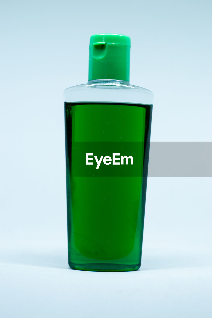 Close-up of green bottle against blue background