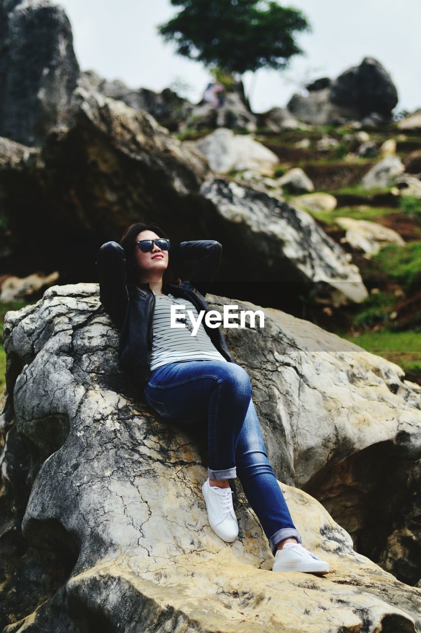 Full length of young woman relaxing on rock