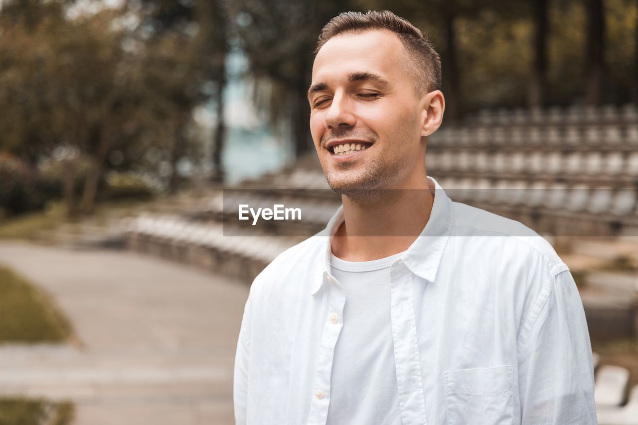 PORTRAIT OF SMILING YOUNG MAN LOOKING AWAY