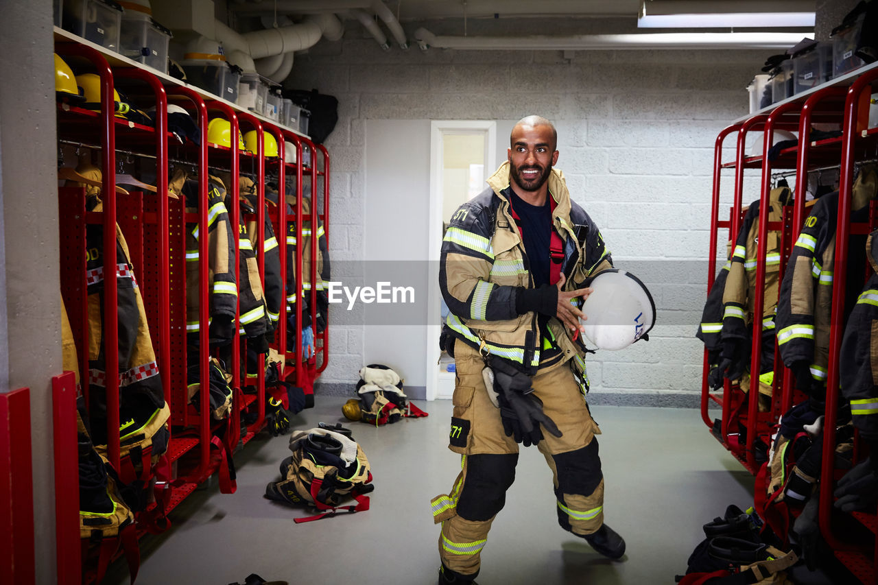 Male firefighter holding work helmet in locker room at fire station