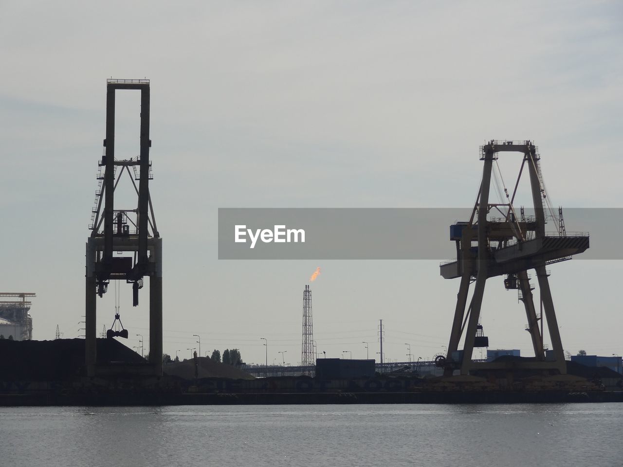 Crane at dock by sea against sky