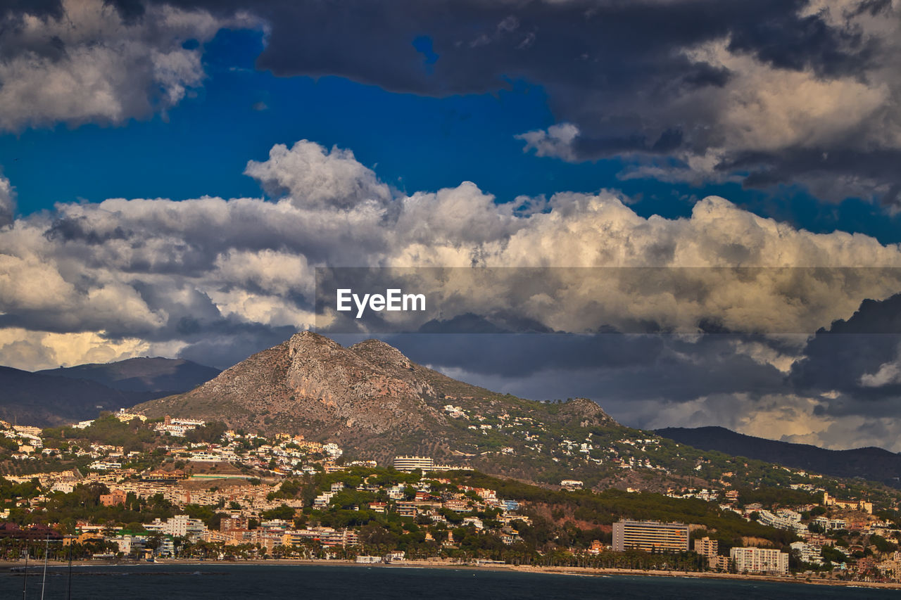 View of townscape by mountain against cloudy sky