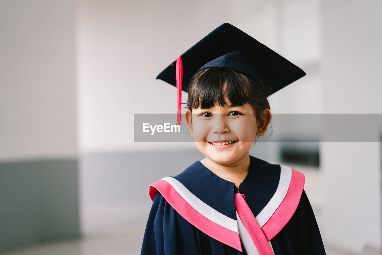 graduation, achievement, graduation gown, student, mortarboard, school, education, university, success, happiness, university student, academic dress, learning, smiling, emotion, portrait, cheerful, diploma, certificate, child, pride, looking at camera, positive emotion, event, campus, intelligence, aspirations, one person, copy space, tassel, ceremony, childhood, high school student, life events, standing, women, motivation, school building, celebration, smile, teeth, young adult, adult, adult student, joy, female