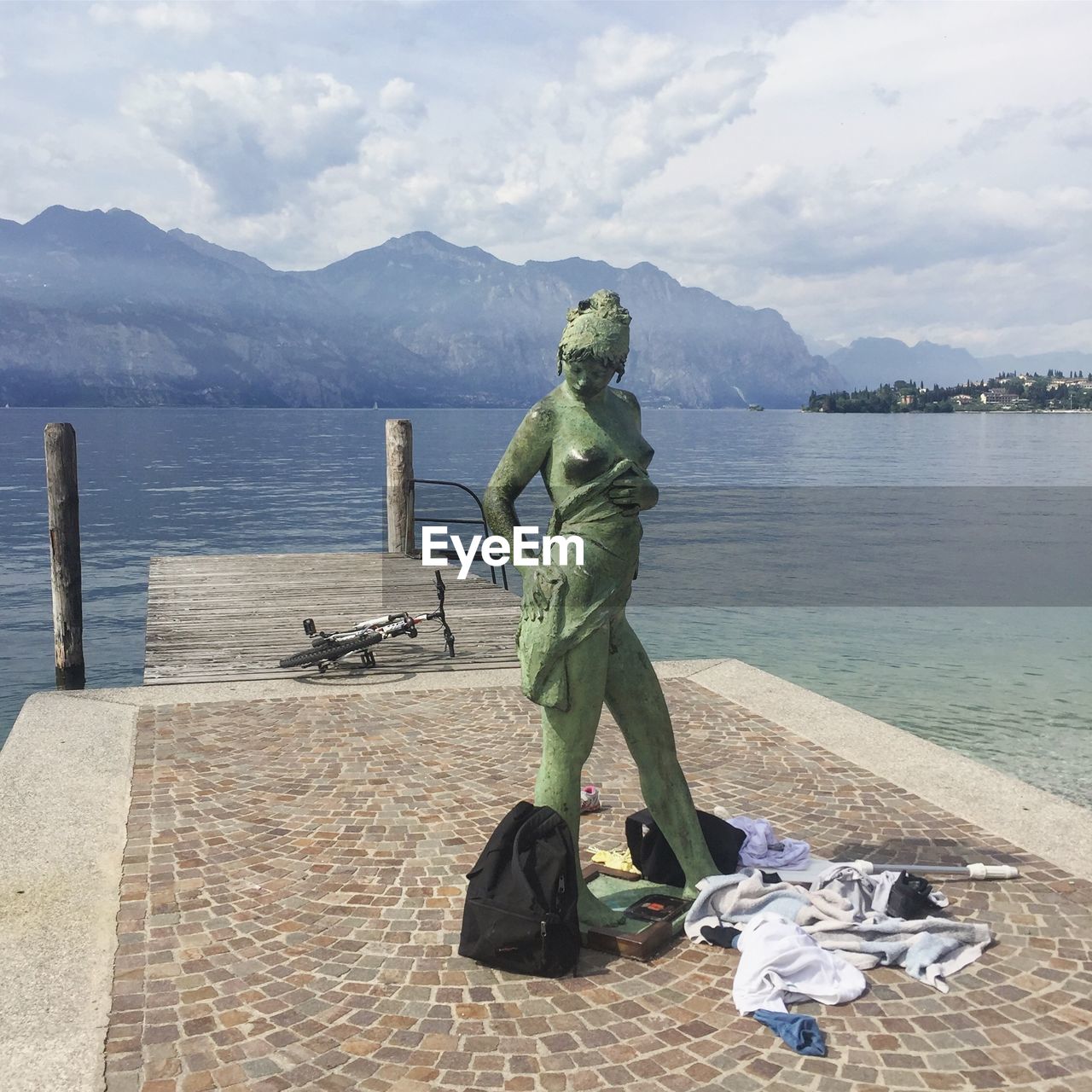 STATUE BY LAKE AGAINST MOUNTAIN