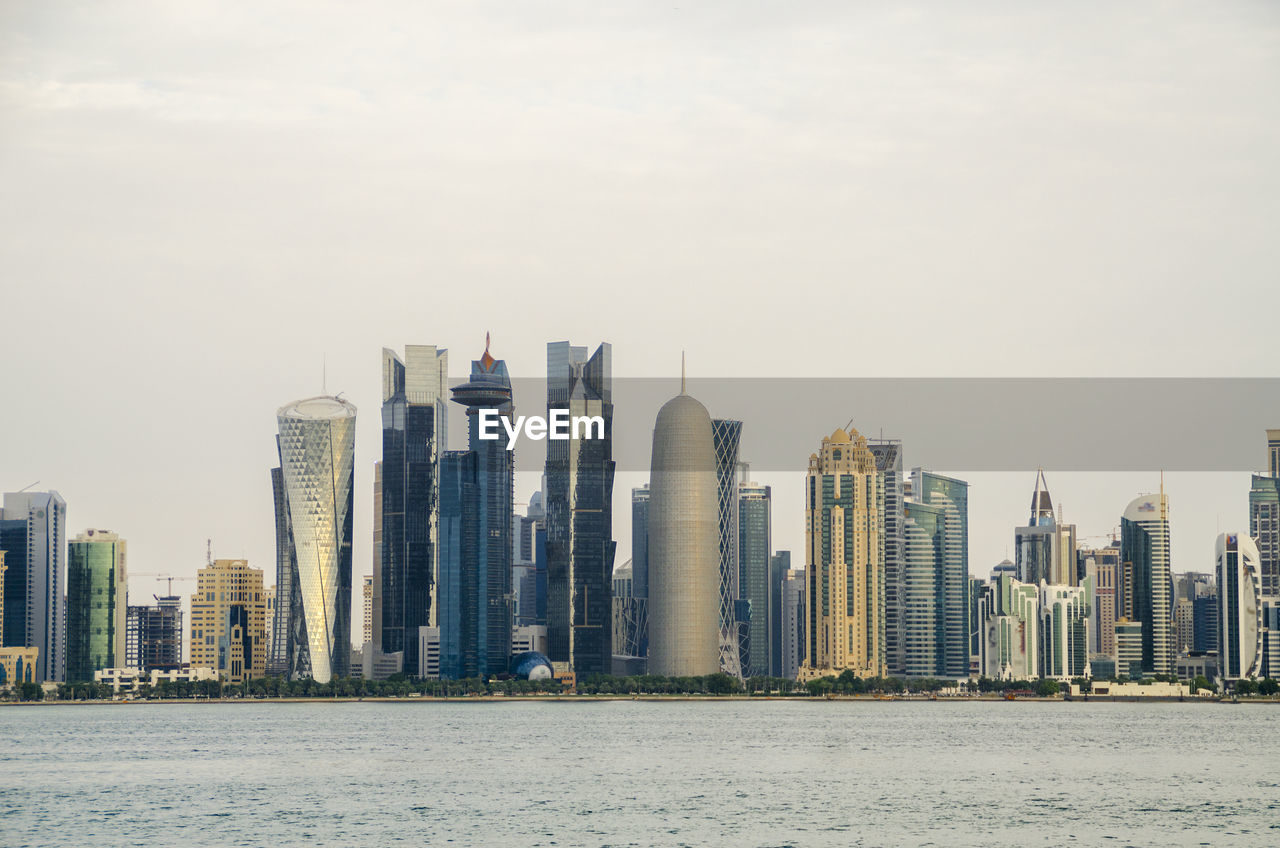 Sea by modern buildings against sky in city