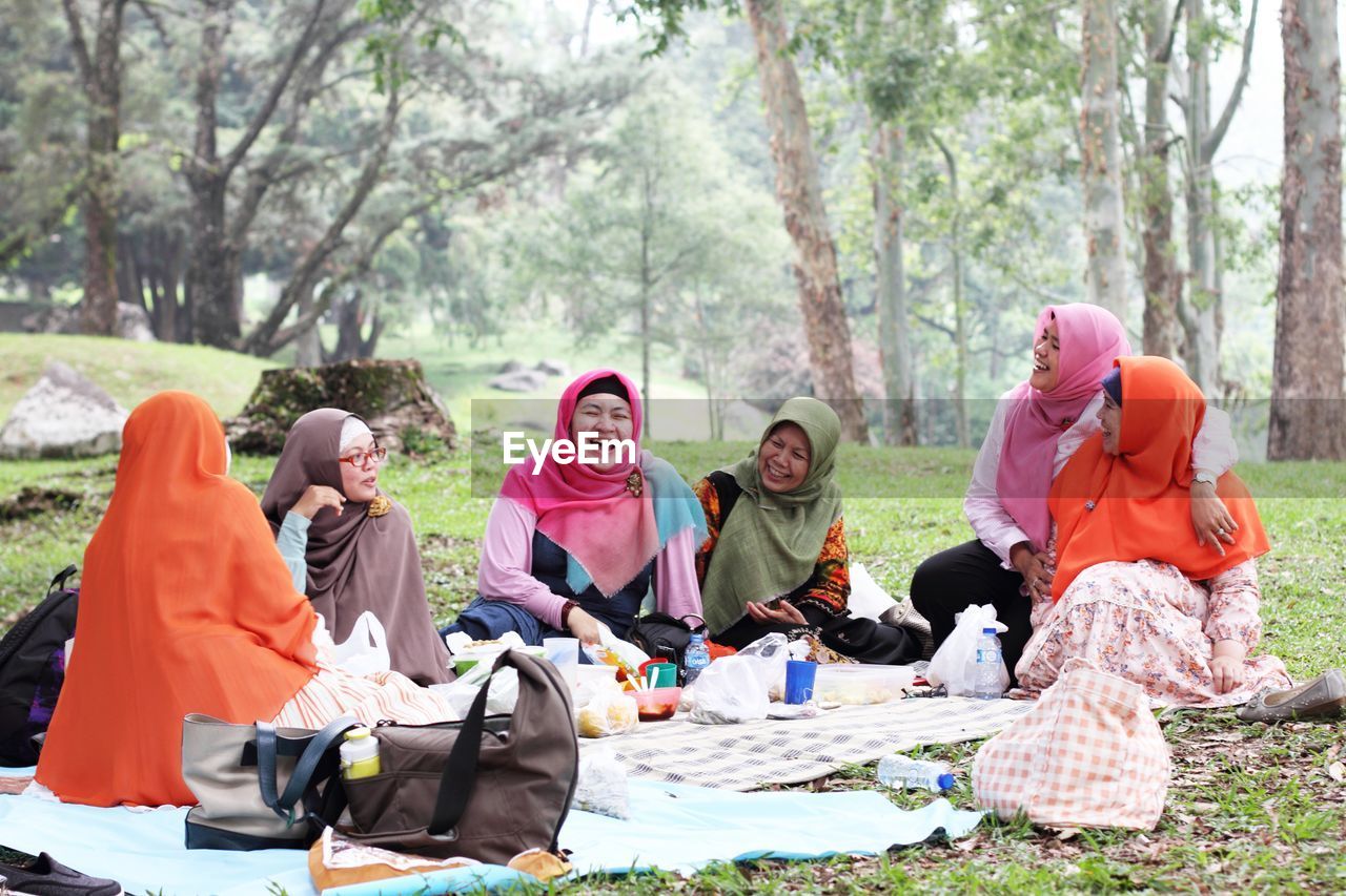 Smiling friends wearing hijab while enjoying in picnic