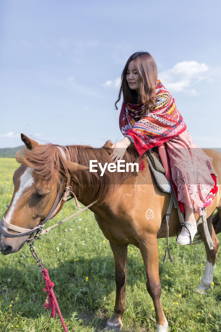 WOMAN RIDING HORSE ON FIELD