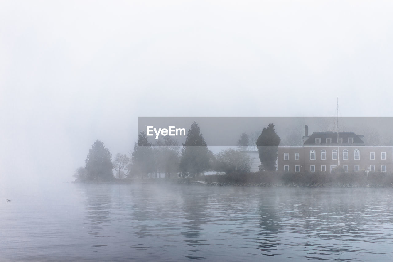 Scenic view of sea against house during foggy weather