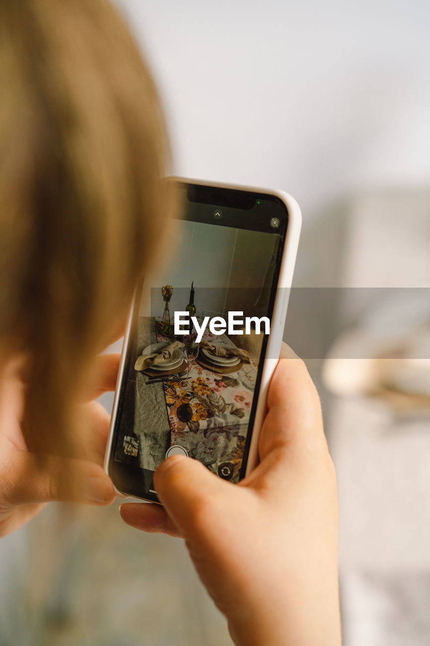 Video blog. a young woman is filming kitchen goods for her online store on her phone camera.