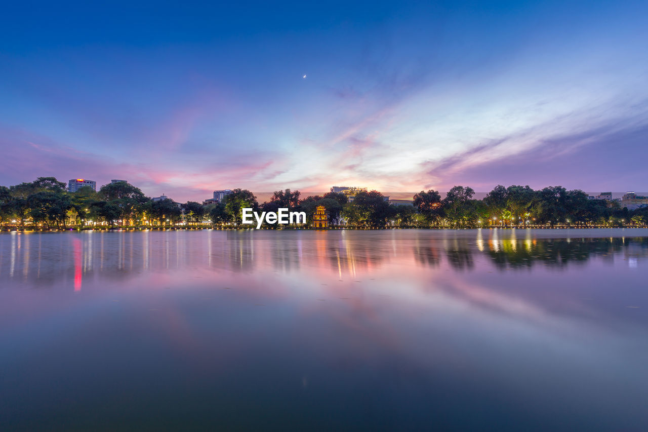 Scenic view of lake against dramatic sky at sunset