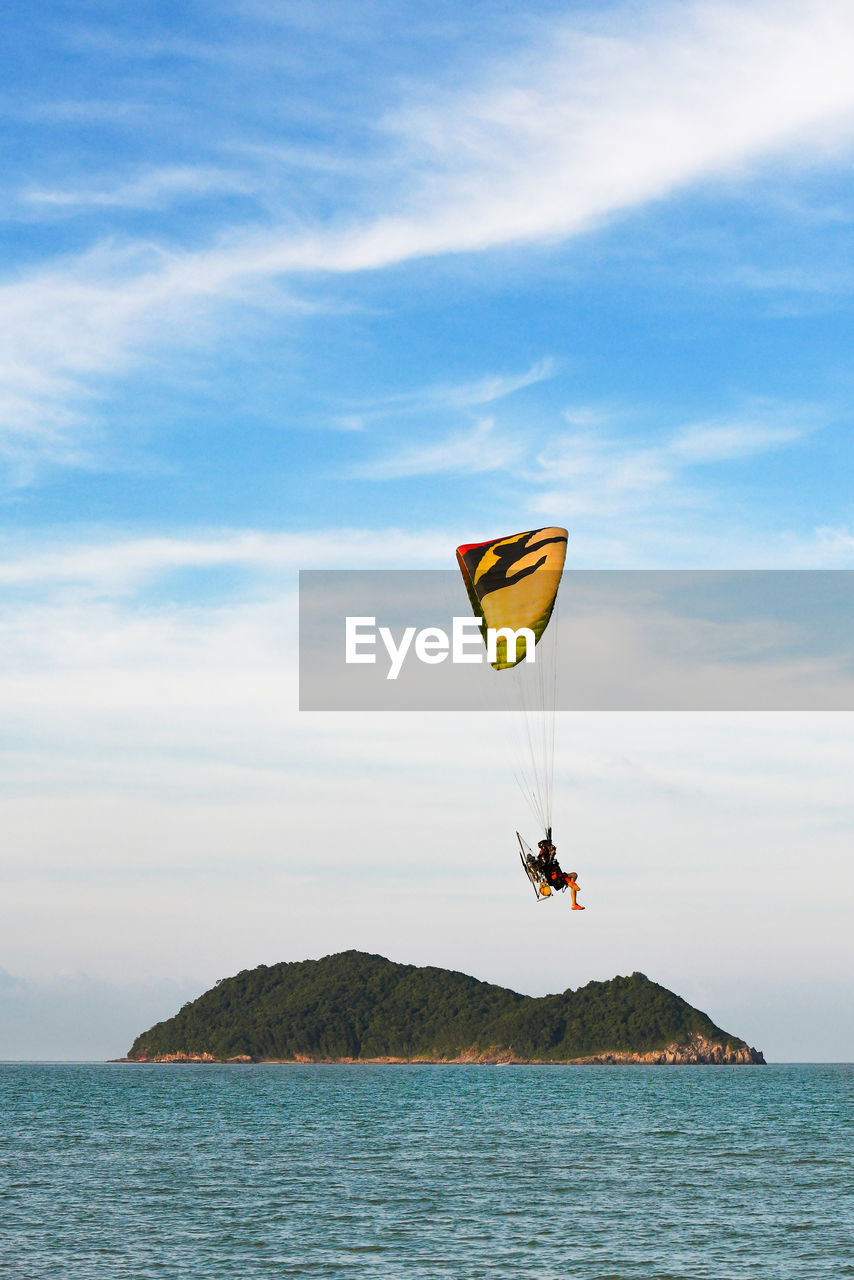 Low angle view of man paragliding over sea