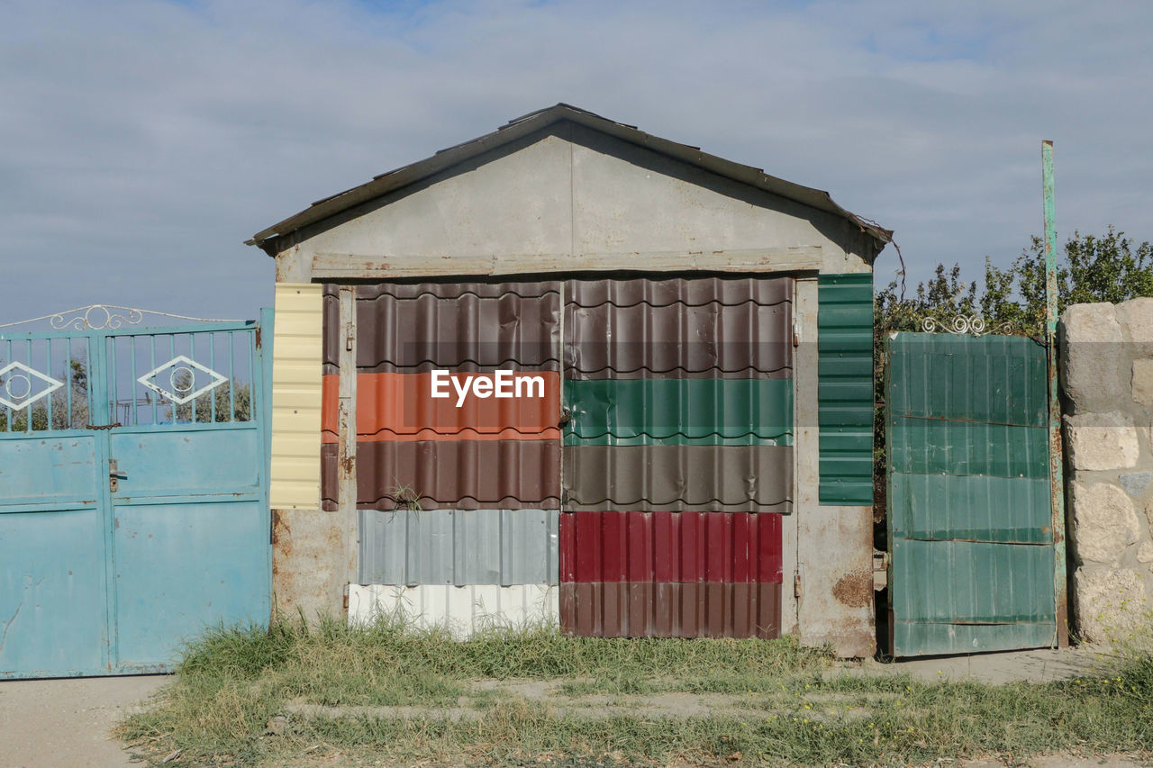 shed, architecture, built structure, sky, nature, building exterior, building, hut, shack, barn, facade, beach hut, no people, house, beach, day, cloud, land, shipping container, wall, outdoors, rural area, plant, wood, multi colored, outdoor structure, landscape, water