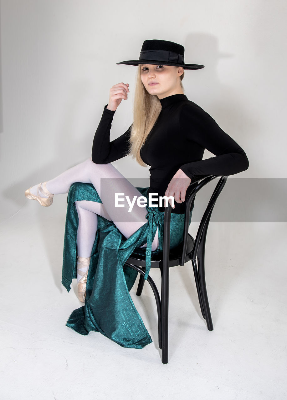 YOUNG WOMAN WEARING HAT SITTING ON SEAT