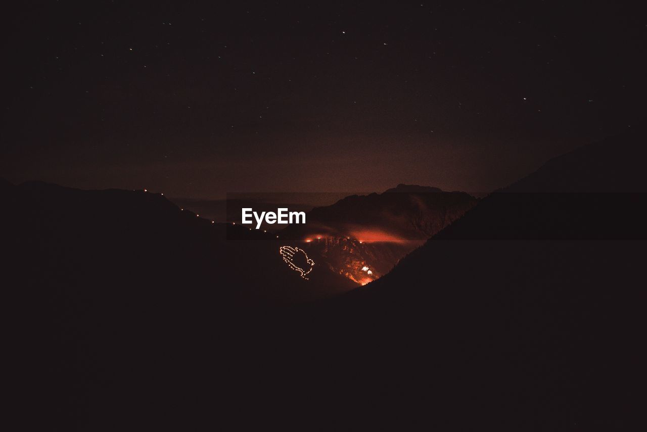 SCENIC VIEW OF ILLUMINATED MOUNTAIN AGAINST SKY AT NIGHT