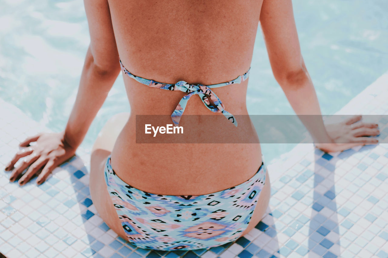 Midsection of woman in bikini swimming pool