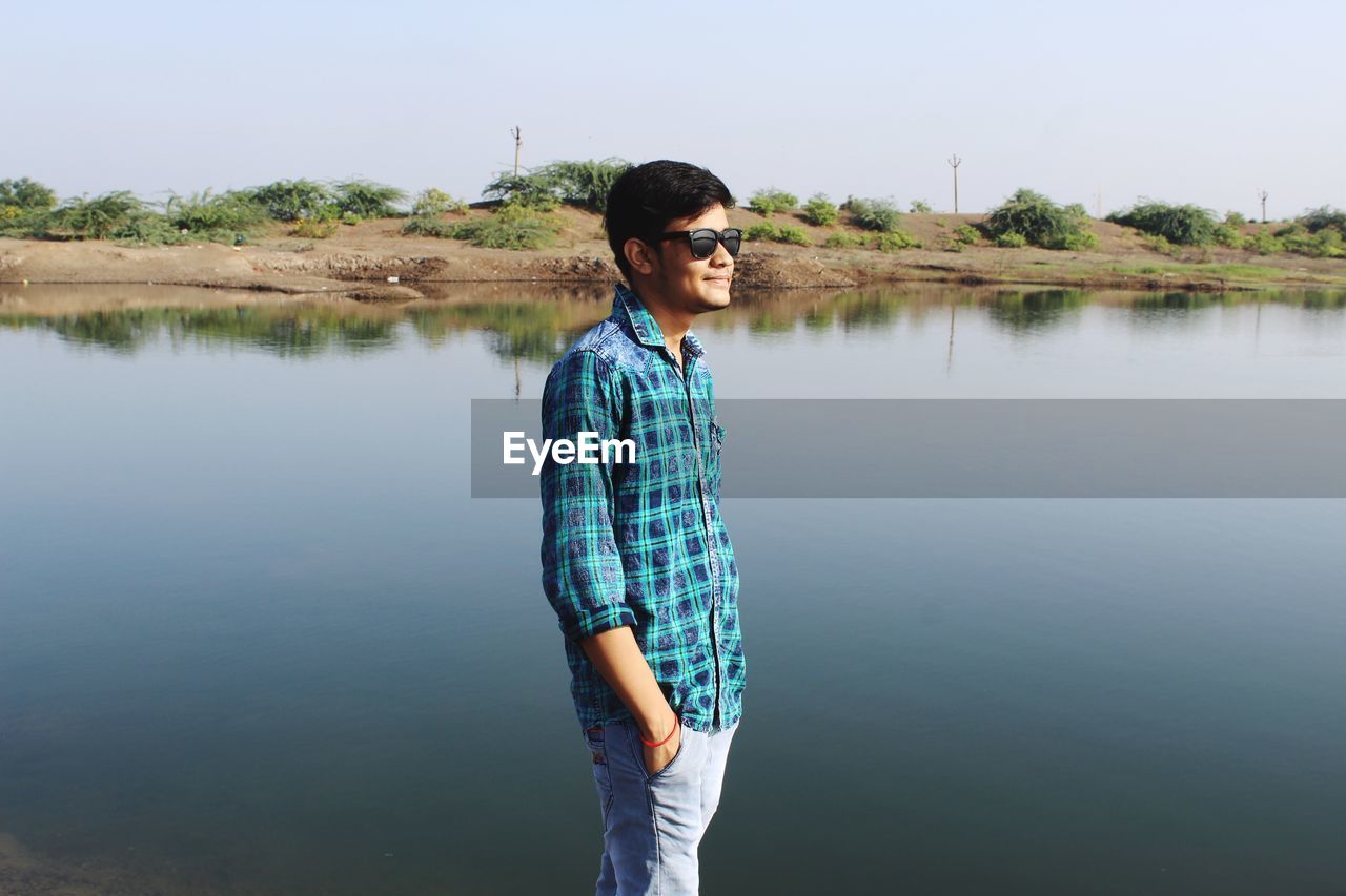 Young man standing by lake