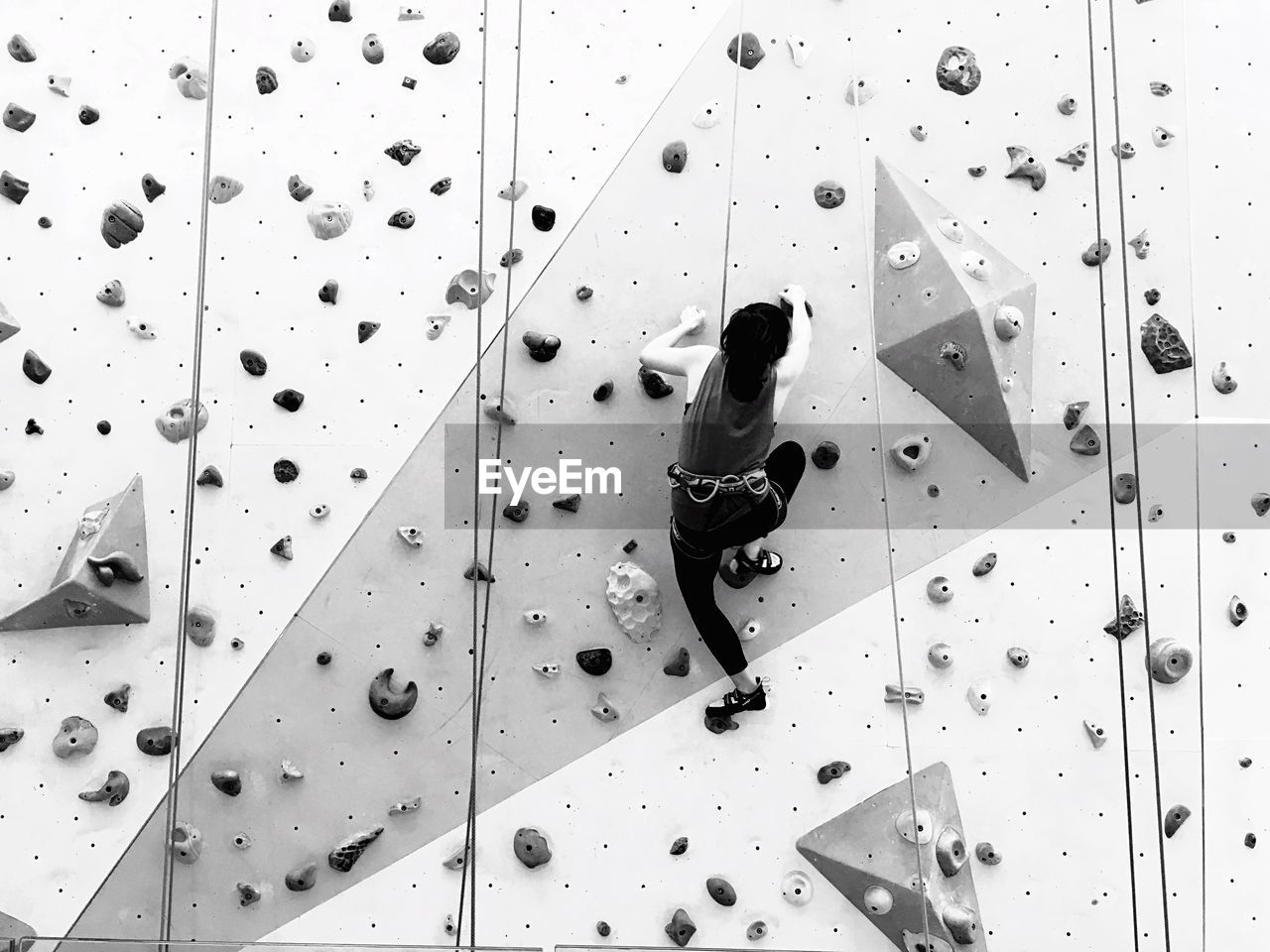 Low angle view of woman practicing rock climbing at gym