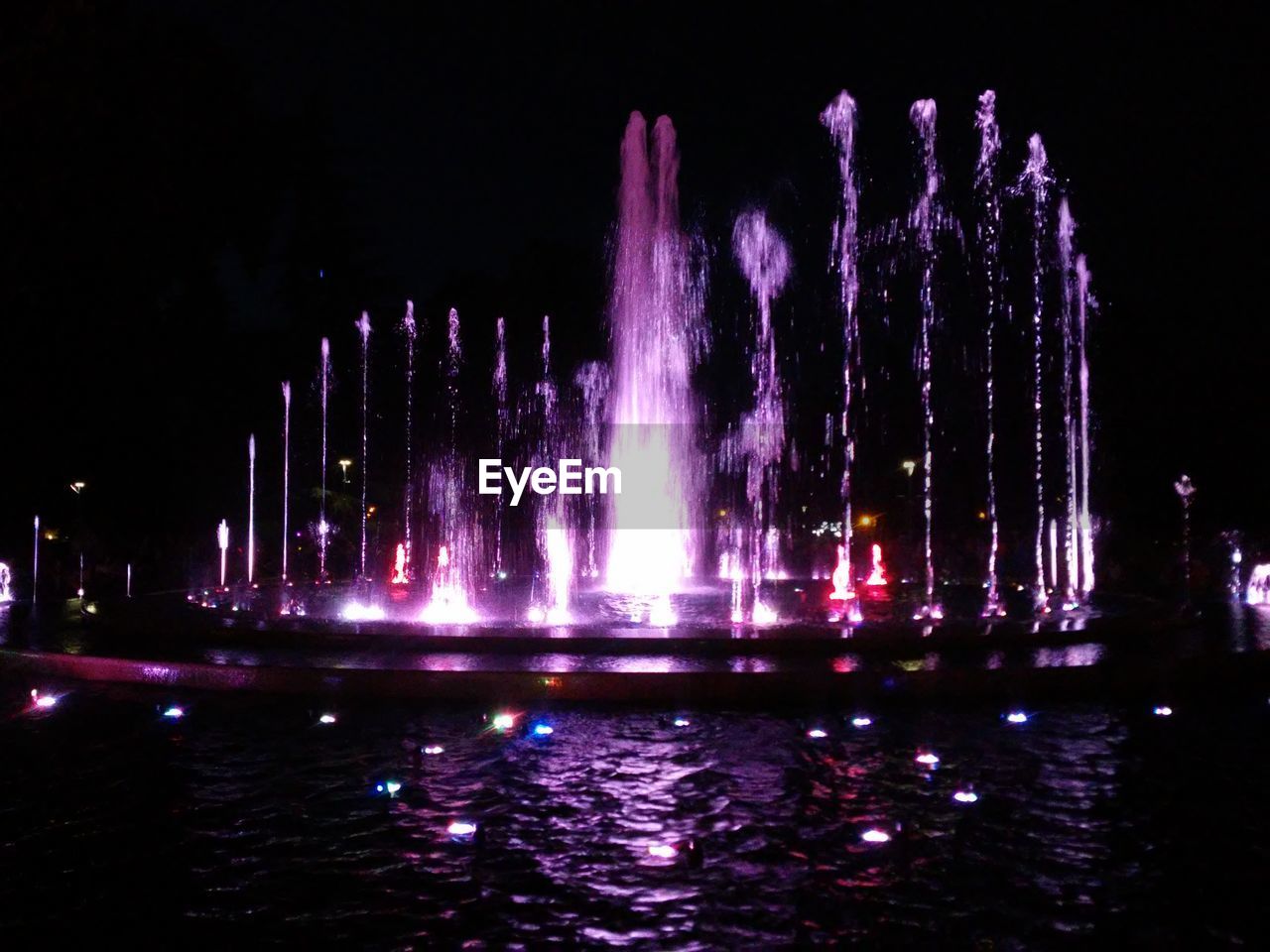 REFLECTION OF ILLUMINATED CITY IN WATER AT NIGHT