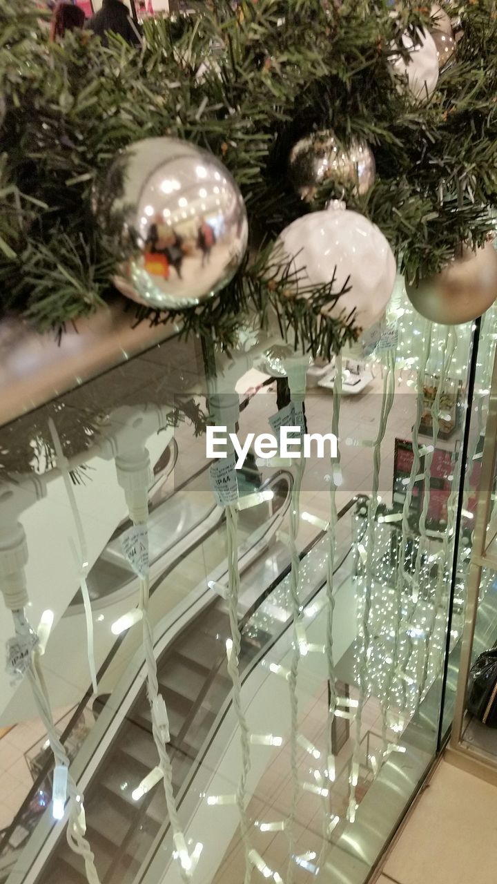 Christmas tree by lighting on glass railing in shopping mall