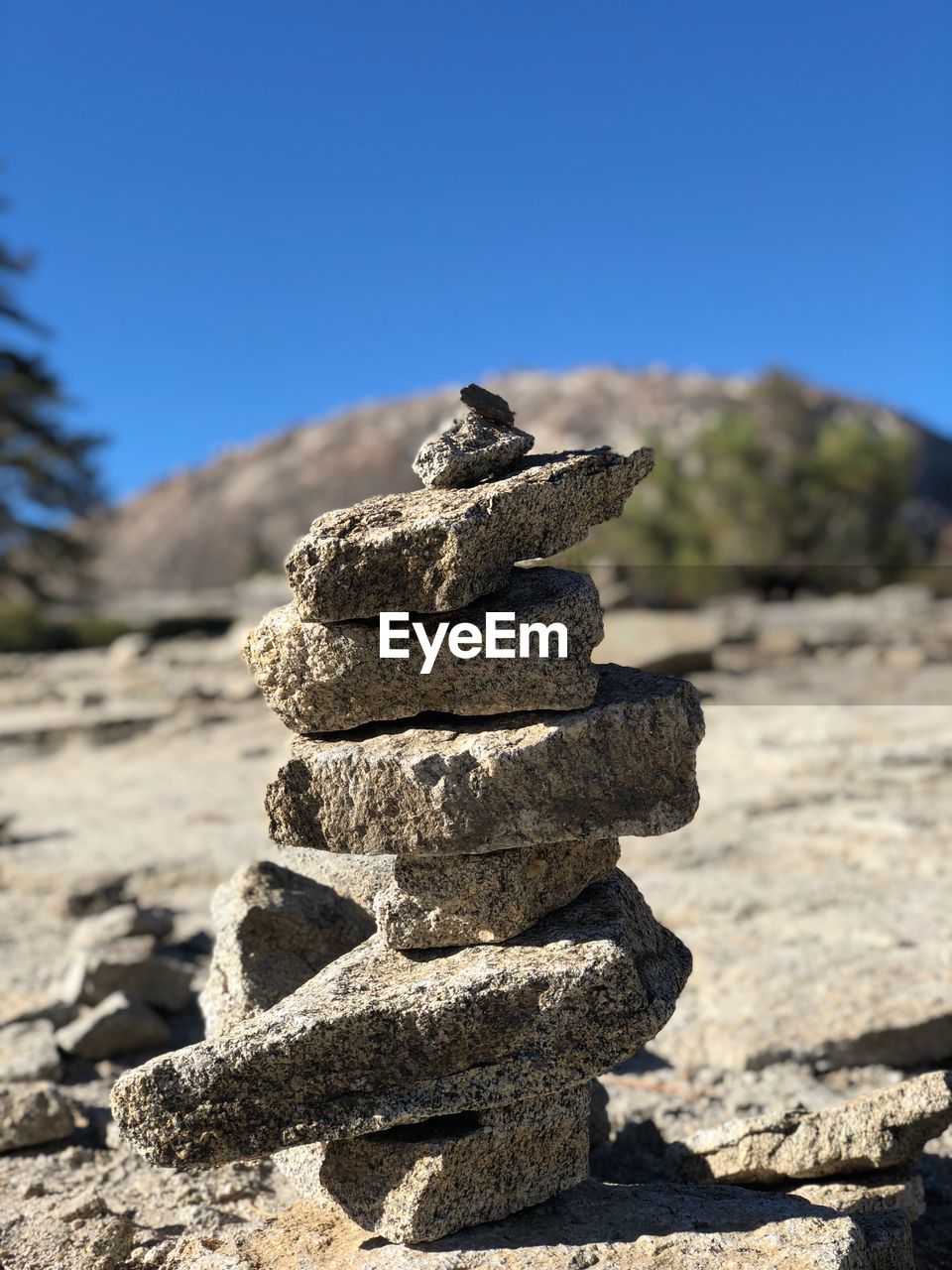 Close-up of stacked stones on mountain against clear blue sky
