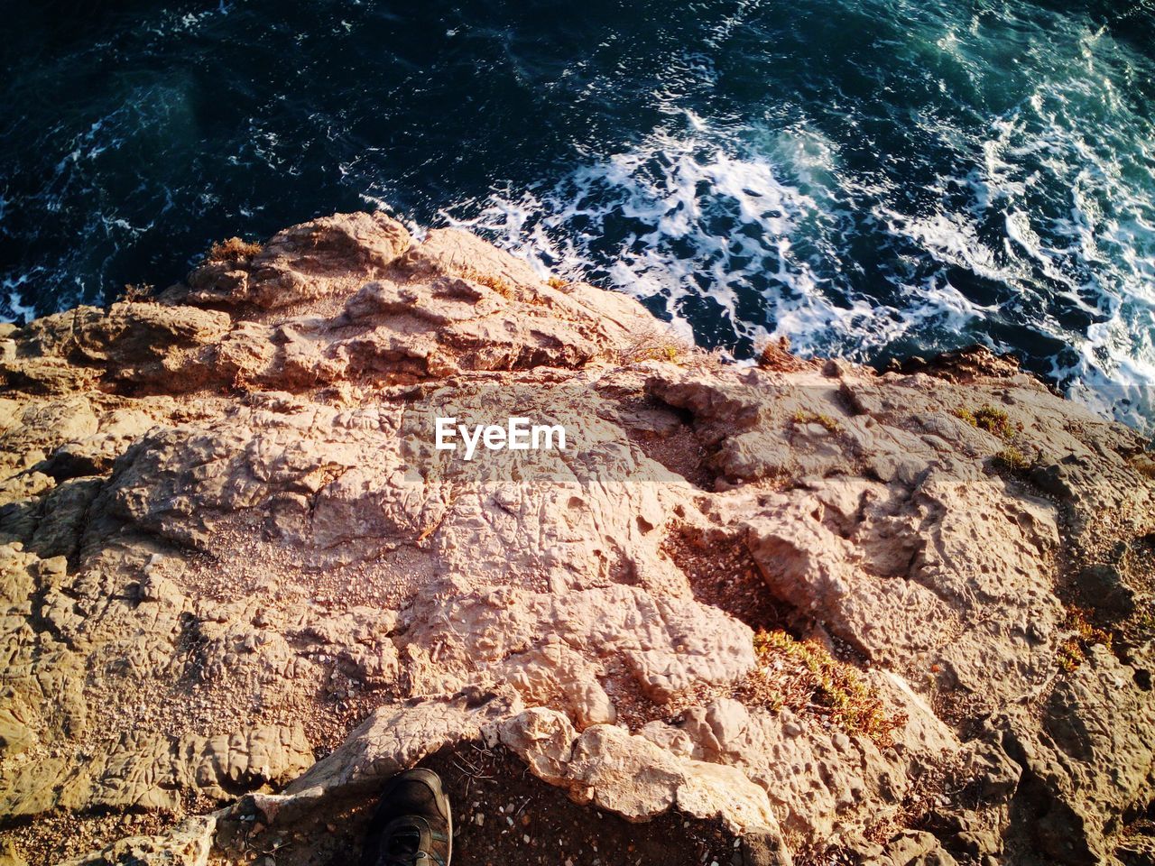 CLOSE-UP OF ROCK FORMATION AT SEA