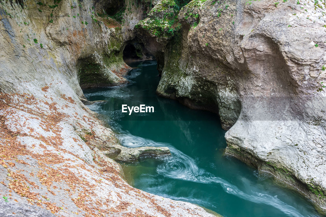 water, beauty in nature, rock, nature, scenics - nature, rock formation, no people, river, land, non-urban scene, tranquility, day, environment, high angle view, body of water, outdoors, tree, geology, plant, travel destinations, forest, travel, tranquil scene, idyllic, water feature, cave, wadi, landscape, physical geography, motion, waterfall, sea cave, stream