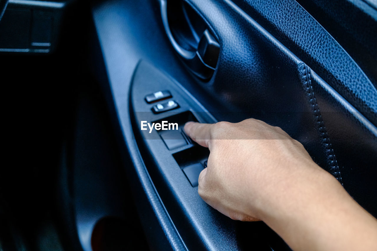 Cropped hand touching push button on car door