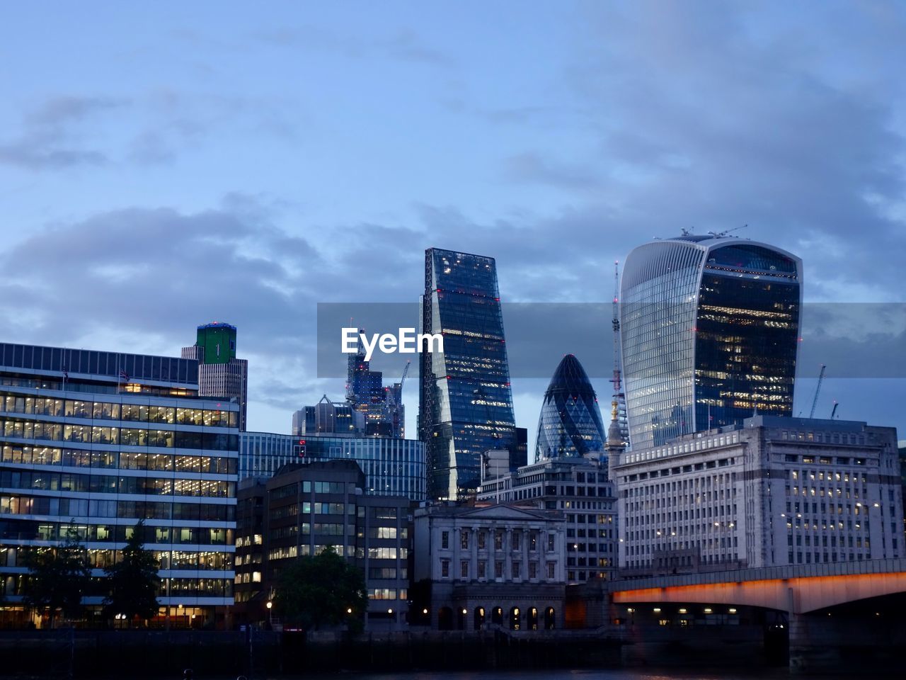 Modern buildings in city against sky at dusk