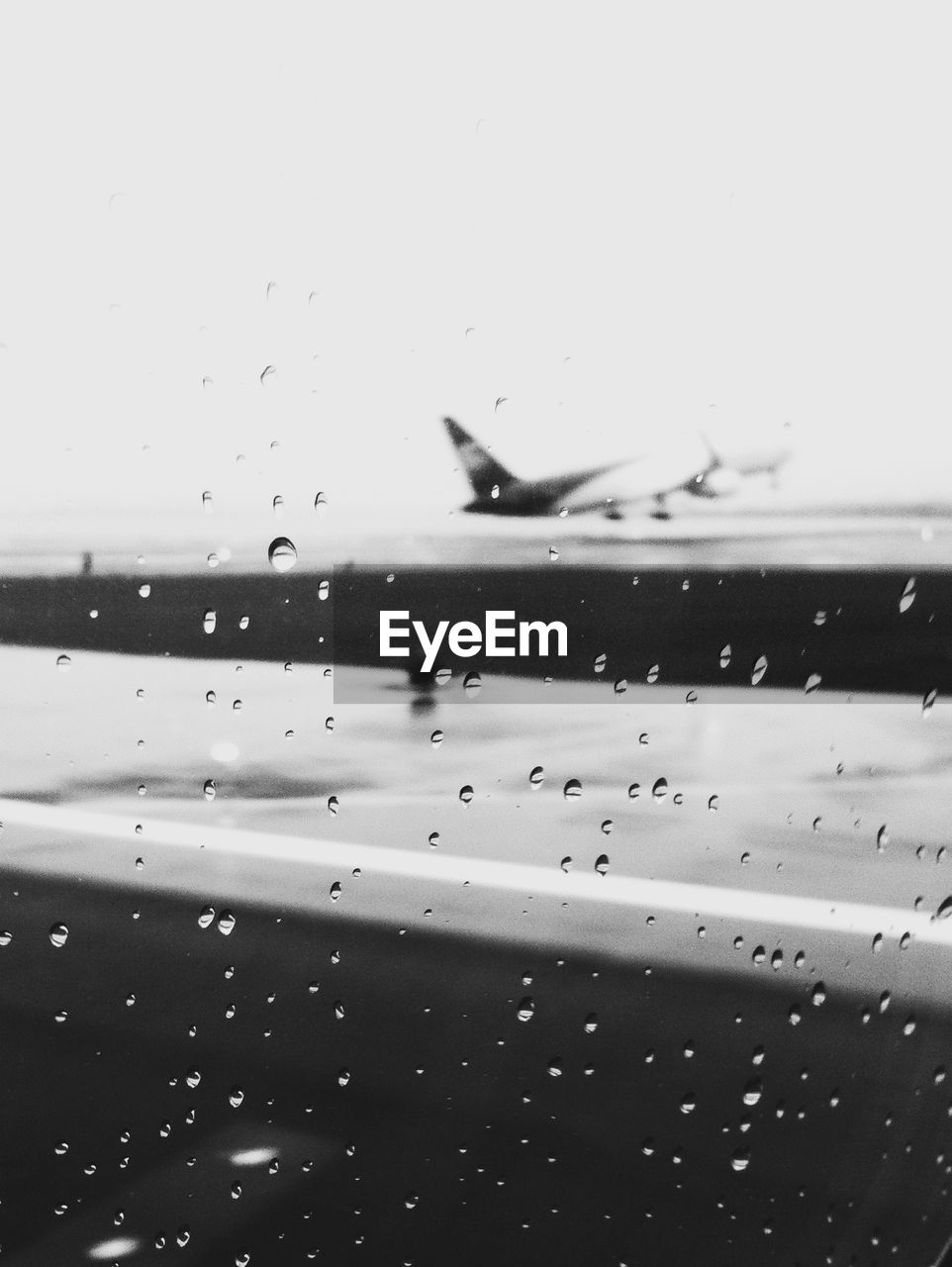 Airplanes and runway seen through wet window