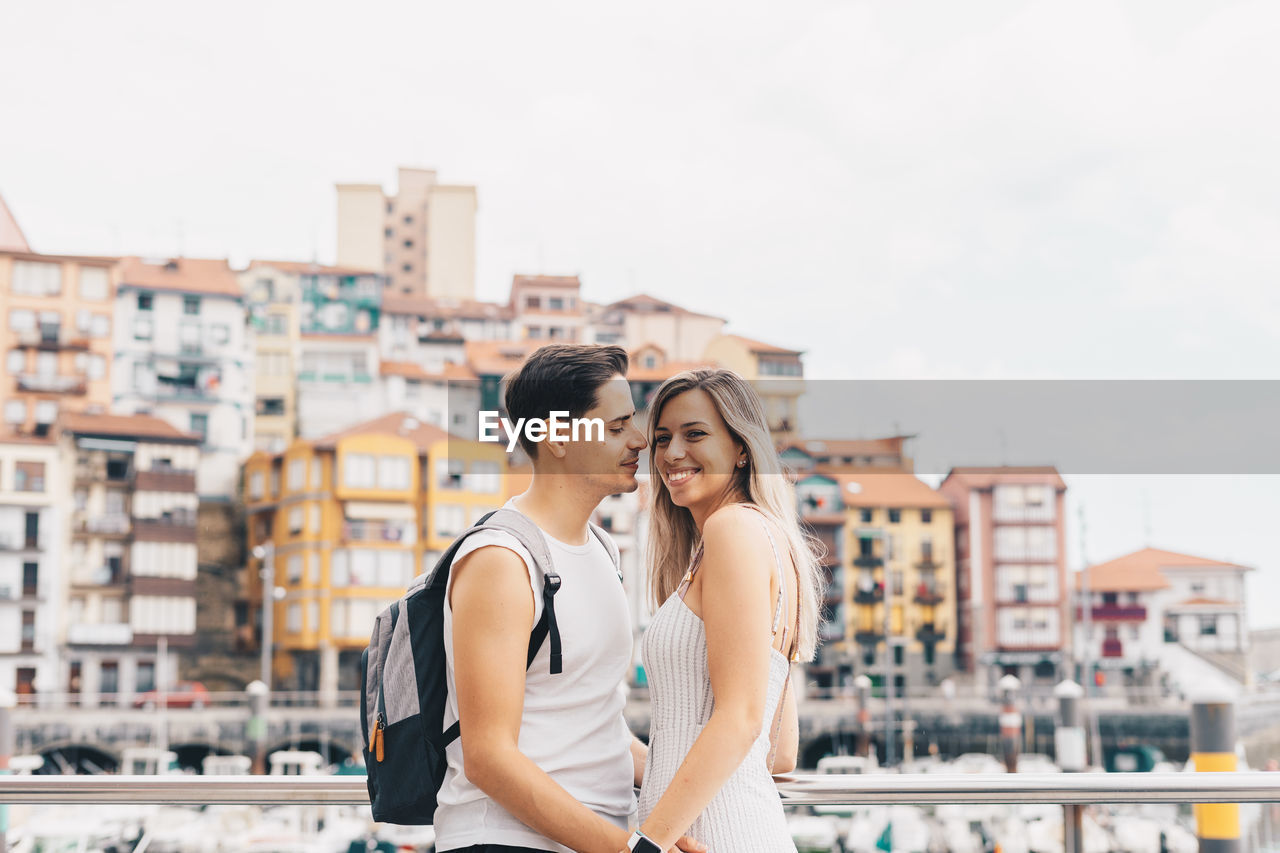 Couple embracing while standing against cityscape