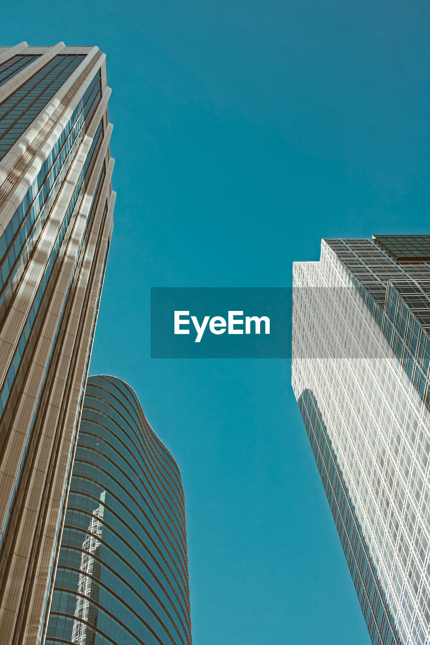 Low angle view of modern buildings against clear blue sky