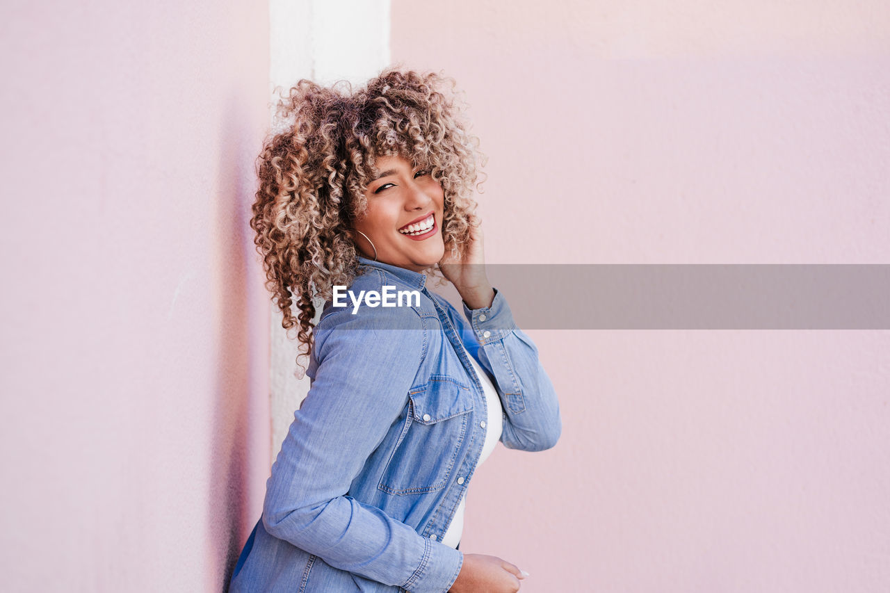 Portrait of smiling hispanic woman with afro hair in city during spring. urban lifestyle