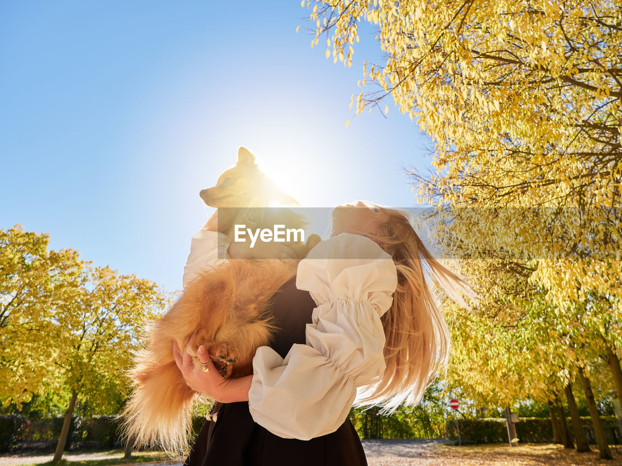 MIDSECTION OF WOMAN WITH UMBRELLA AGAINST SKY