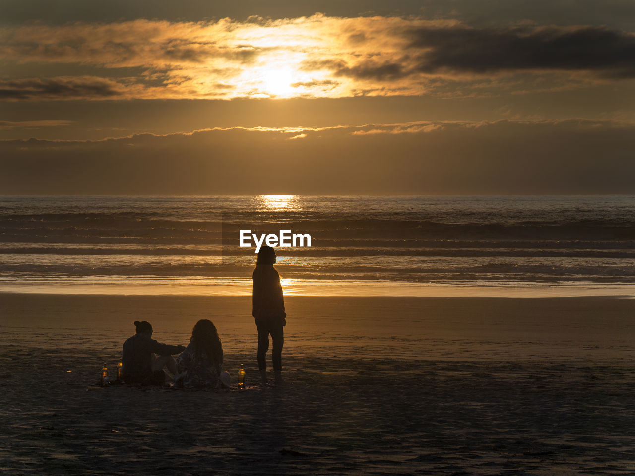 Silhouette people on beach against sky during sunset