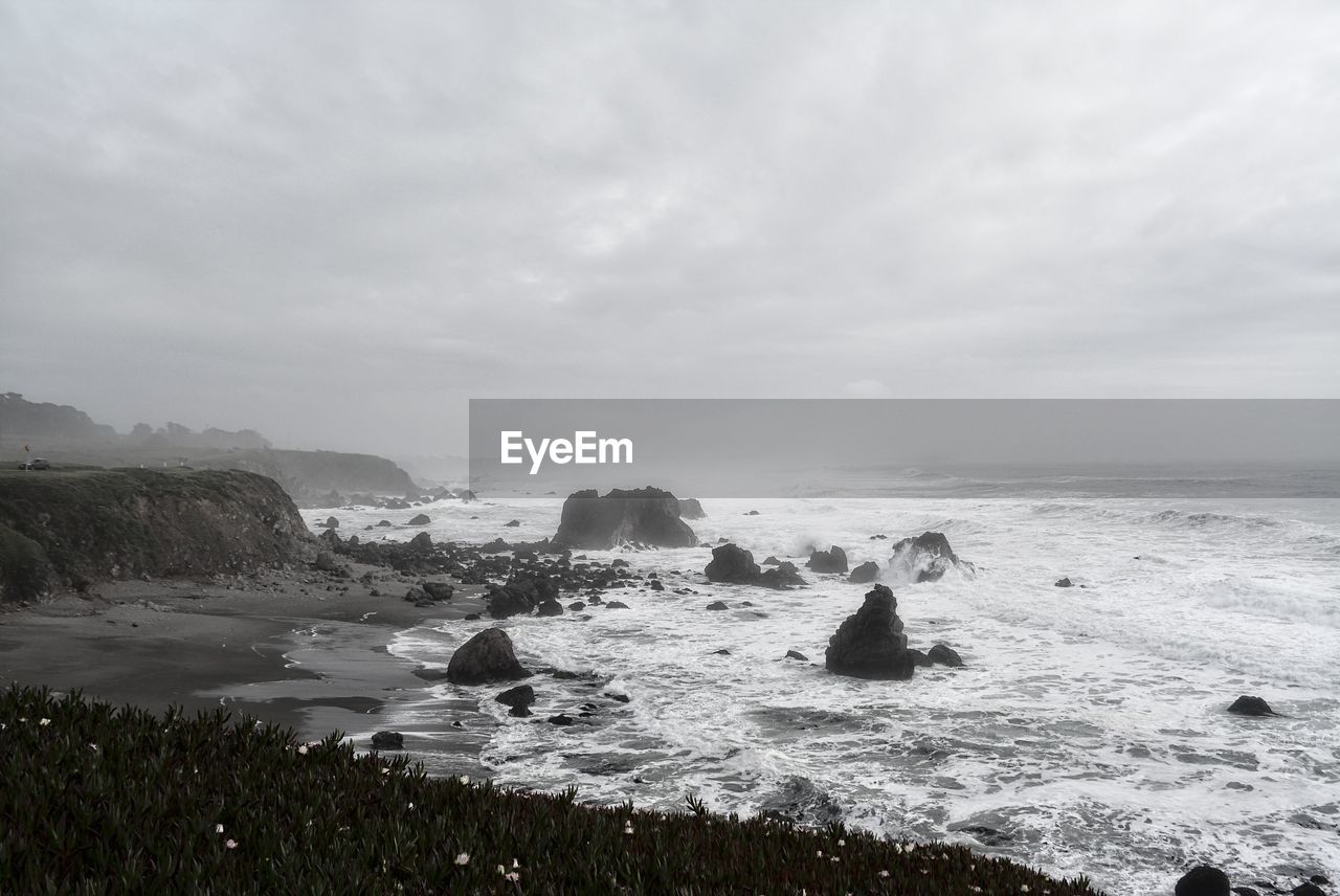 ROCKS IN SEA AGAINST SKY