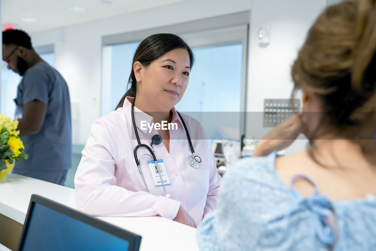 Doctor looking at female colleague with male coworker in background