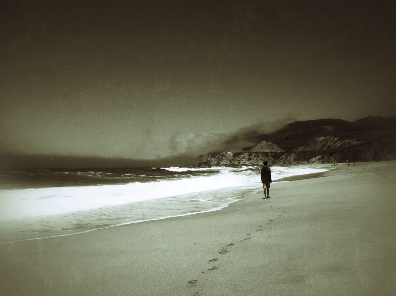 Rear view of boy walking on beach against sky