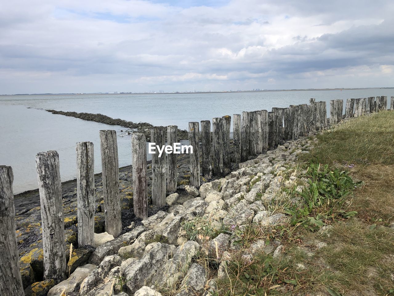 PANORAMIC SHOT OF WOODEN POSTS ON SEA AGAINST SKY