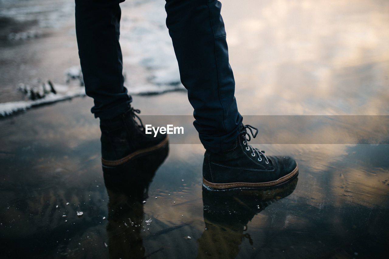 Low section of man standing in a frozen lake